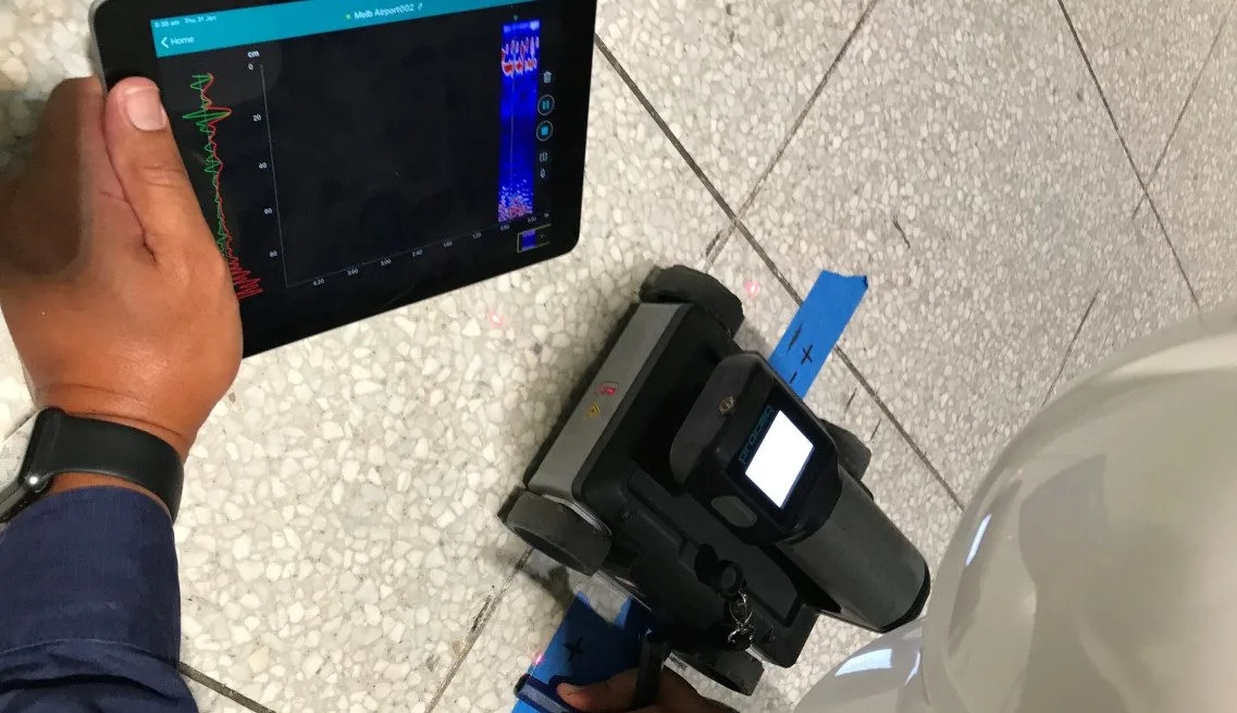 Technician using GPR concrete scanning equipment to detect embedded services in a concrete slab