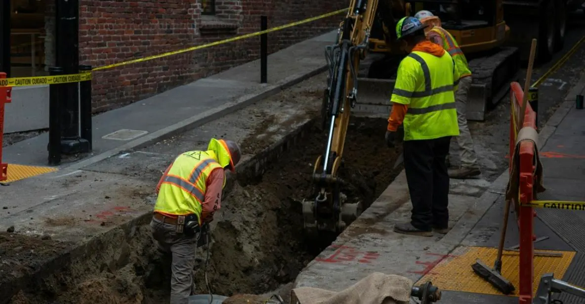 Utility workers excavating a trench to expose underground services before installation