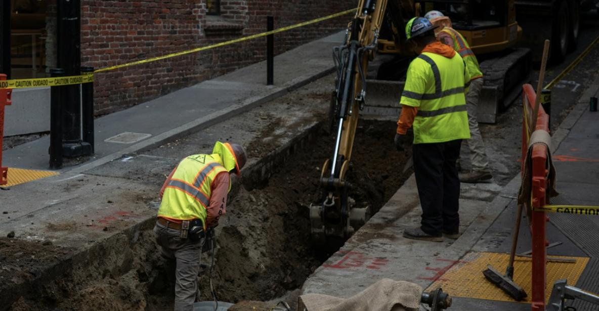 Utility workers excavating a trench to expose underground services before installation